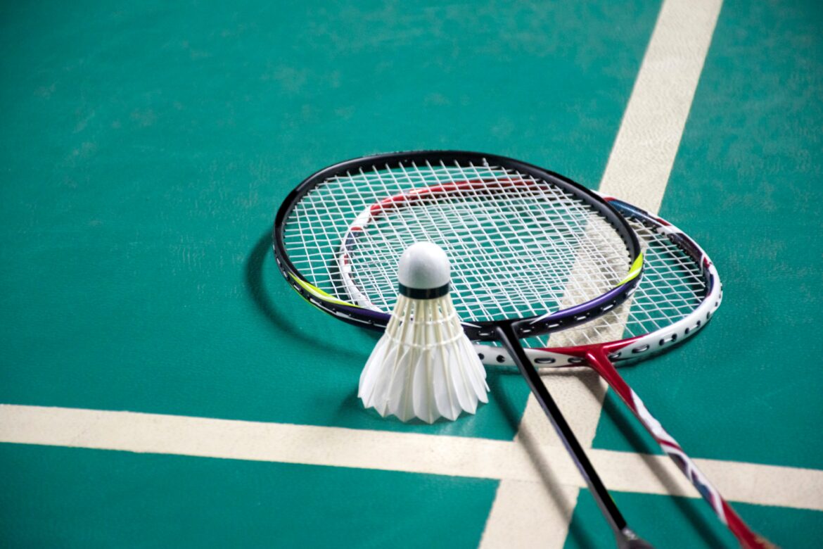 Badminton sport equipments, rackets and shuttlecocks on dark floor of indoor badminton court, soft focus, concept for badminton playing lovers around the world, copy space.