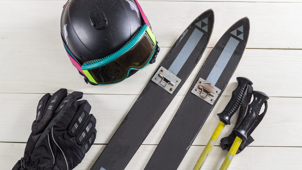 Skiing gears including ski helmet, ski gloves, ski boards and ski poles placed on a white table