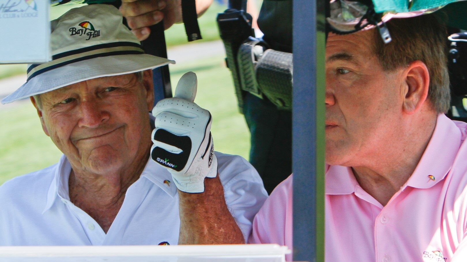 Arnold Palmer showing thumbs up gesture to his fans while sitting in a golf cart